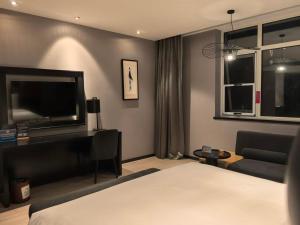 a bedroom with a bed and a television and a couch at Orange Hotel Beijing Summer Palace in Beijing