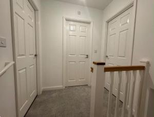 a hallway with two white doors and a staircase at Elegant King Room with Wifi & Parking in Milton Keynes