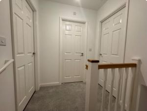 a hallway with two white doors and a staircase at Elegant King Room with Wifi & Parking in Milton Keynes +6 photos