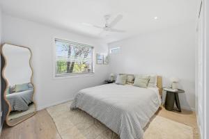 a white bedroom with a bed and a window at Tamara Coastal Retreat in Inverloch