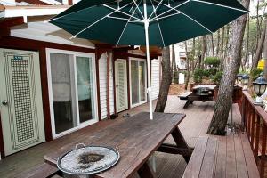 a wooden table with an umbrella on a deck at Sarangiimeomuneunjip Pension in Taean