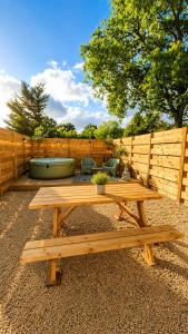 a wooden picnic table in a backyard with a fence at Gite de charme avec jaccuzzi privé in Coëx