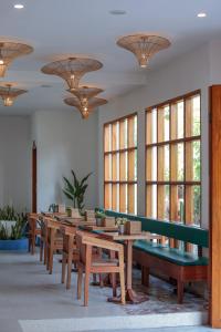 a row of tables and benches in a room with windows at Yulaman Hotel in Gili Trawangan