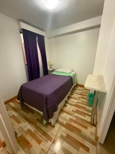 a small bedroom with a bed and a wooden floor at Le Grey Arica in Arica