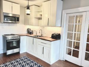 a kitchen with white cabinets and a sink at Stylish Heritage Gem facing Stewart Park and Town Hall in Perth