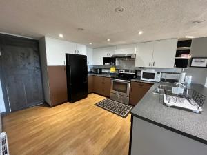 a kitchen with white cabinets and a black refrigerator at Lantzbnb front view in Lantzville +17 photos