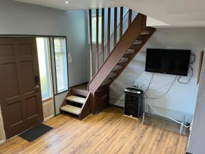 a living room with a staircase with a tv and a door at Lantzbnb front view in Lantzville