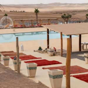 a resort in the desert with a pool and a roller coaster at Kal Tenere Luxury Camp in El Karia