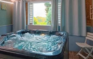 a large bath tub in a room with a window at Maison Mitoyenne Avec Spa in La Chapelle-Urée