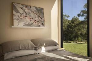 a bed in a room with a large window at Tiny Tallowood by Tiny Away in Glenreagh