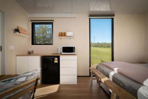 a room with a bed and a kitchen with a microwave at Tiny Tallowood by Tiny Away in Glenreagh
