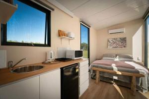 a small kitchen with a bed and a sink in a tiny house at Tiny Tallowood by Tiny Away in Glenreagh