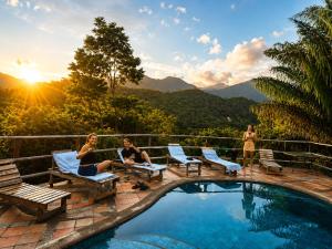 a group of people sitting around a swimming pool at Finca Carpe Diem Ecolodge in Minca