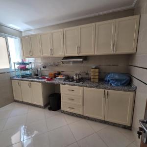 a kitchen with white cabinets and a counter top at Lmadghri6 in Ras El Ma