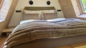 a bed with a blanket on it in a bedroom at Fészek Lombház in Kismaros