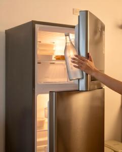 a person holding a bottle in an open refrigerator at Hooga Home in Cebu City