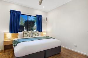 a bedroom with a large bed with blue curtains at Dunes Escape in Broome