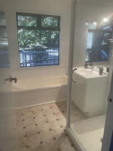 a bathroom with a shower and a sink and a window at Kapanga Escape in Coromandel Town