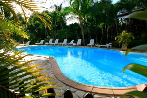 a large swimming pool with lounge chairs and palm trees at Résidence hotelière Habitation Grande Anse in Deshaies
