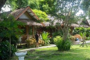 a man standing in front of a house at Butterfly Resort Hostel, Pai in Pai