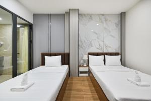 two beds in a hotel room with white sheets at The Crown Airport Hotel in Ho Chi Minh City