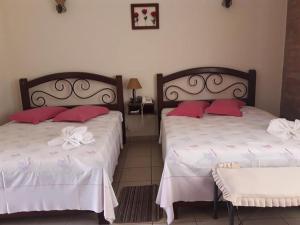 a bedroom with two beds with red pillows at Hotel Balneario Las Tinajitas in Choreti