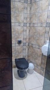 a bathroom with a black toilet and a stone wall at Stilus pousada in Sinop
