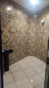 a bathroom with a tiled wall with a toilet and a sink at Stilus pousada in Sinop
