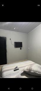 a bedroom with a bed with a tv on the wall at Custo benefício Piri in Pirenópolis +1 photo