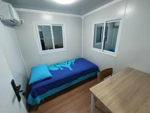 a small bedroom with a blue bed and two windows at KF Logement Wallis in Hihifo Airport