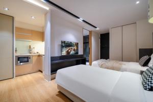 a bedroom with two white beds and a kitchen at Citadines South Chengdu in Chengdu +36 photos