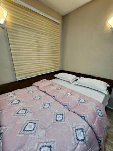 a pink bed in a room with a window at This apartment blends elegance and calm in Mills Center