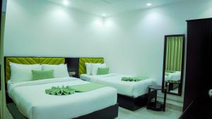 a hotel room with two beds and a mirror at Sylhet Regency Ltd in Sylhet
