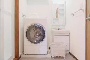 a washing machine in a white laundry room with a sink at Haul Sakuramachi in Kumamoto