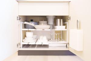 a cupboard filled with dishes and other kitchen utensils at Haul Sakuramachi in Kumamoto
