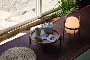 a table with a tea pot and a chair on a porch at Komado ベンガラ in Komatsu