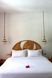 a white bed with a flower on top of it at La Calma Villa in Gili Islands +22 photos