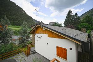 a small white building with a wooden roof with mountains at Xalet Les Avellanes - hut 7335 in Arinsal
