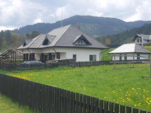 a white house with a fence and a field of grass at Pensiunea Mușata Bucovinei in Vama