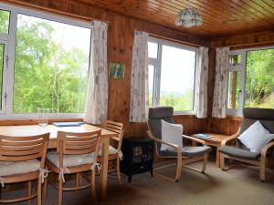 a dining room with a table and chairs and windows at Faichemard Farm Chalets in Invergarry