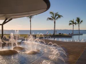 a fountain in a park with palm trees and water at Iluka in Yeppoon