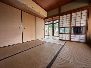 an empty room with mats in a room with windows at 空港近くの温泉宿 翻車魚庵 in Kirishima