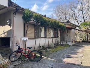 a red bike parked in front of a house at 空港近くの温泉宿 翻車魚庵 in Kirishima