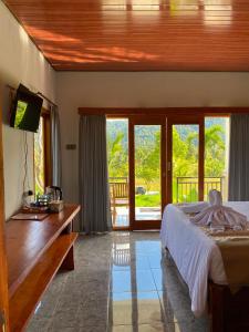 a bedroom with a bed and a television and a balcony at Umaku Bali Homestay in Munduk +20 photos