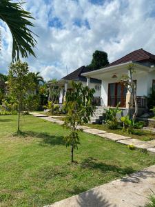 a white house with a tree in the yard at Umaku Bali Homestay in Munduk