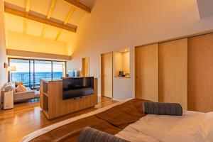 a large living room with a tv and a bed at さざね in Kyonan