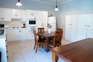 a kitchen with a table and chairs and a refrigerator at Heritage On Horseshoe Guest House in South West Rocks