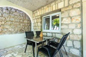 a table and chairs in front of a stone wall at Apartments Dalmatia Blue in Mlini