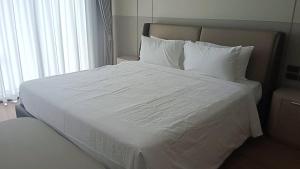 a large white bed with white sheets and pillows at Hermes Haven Hotel in Pattaya South