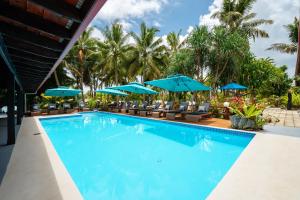 a pool at a resort with chairs and umbrellas at E' Nauwi Beach Resort in Port Vila